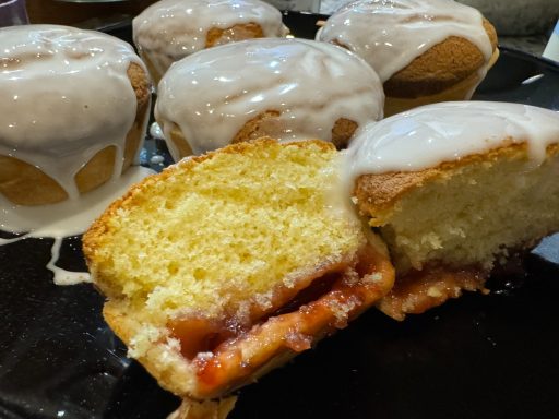 Delicious iced cupcakes with a cut one revealing a strawberry filling.